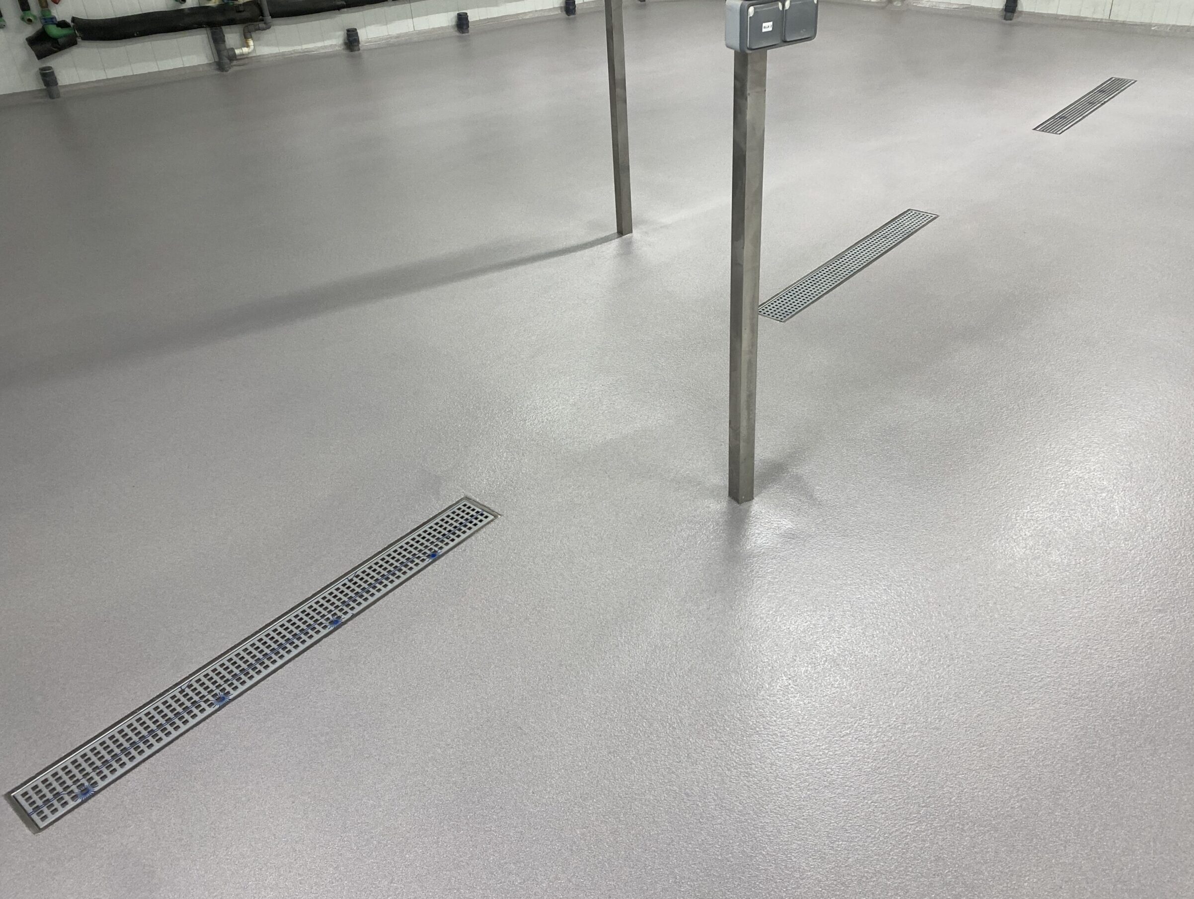 Pavimento de color grisáceo de resina de metacrilado con canales de drenaje correctamente integradas en la superficie.