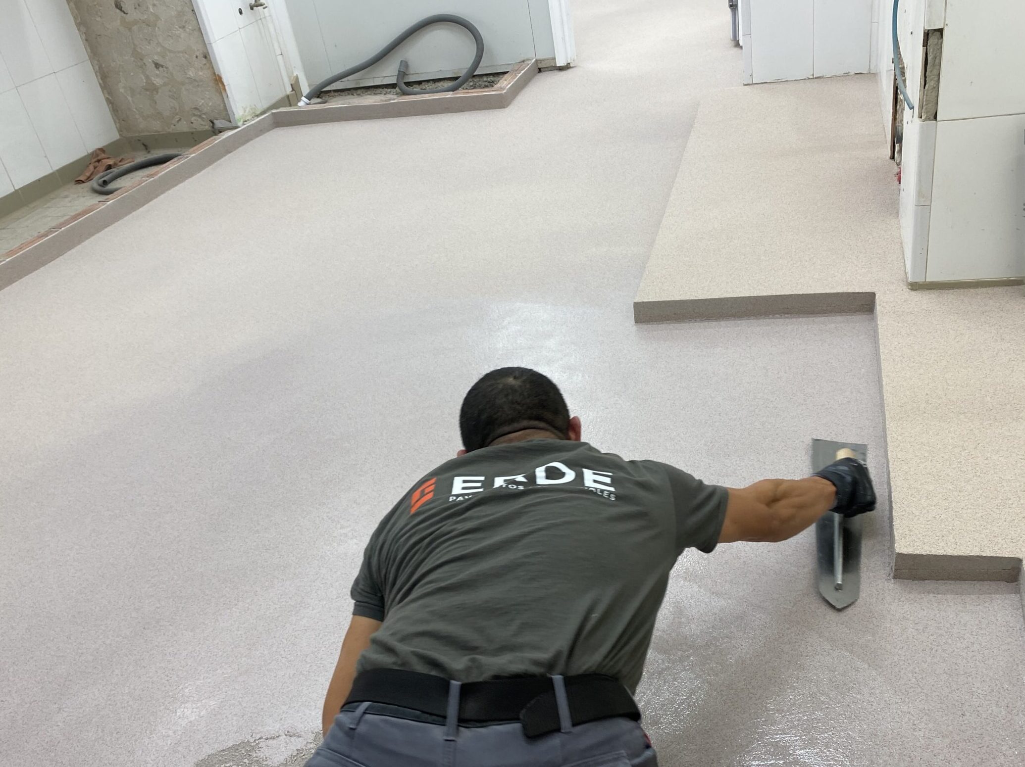 Operario aplicando una de las capas de pavimento sobre la superficie anteriormente preparada.