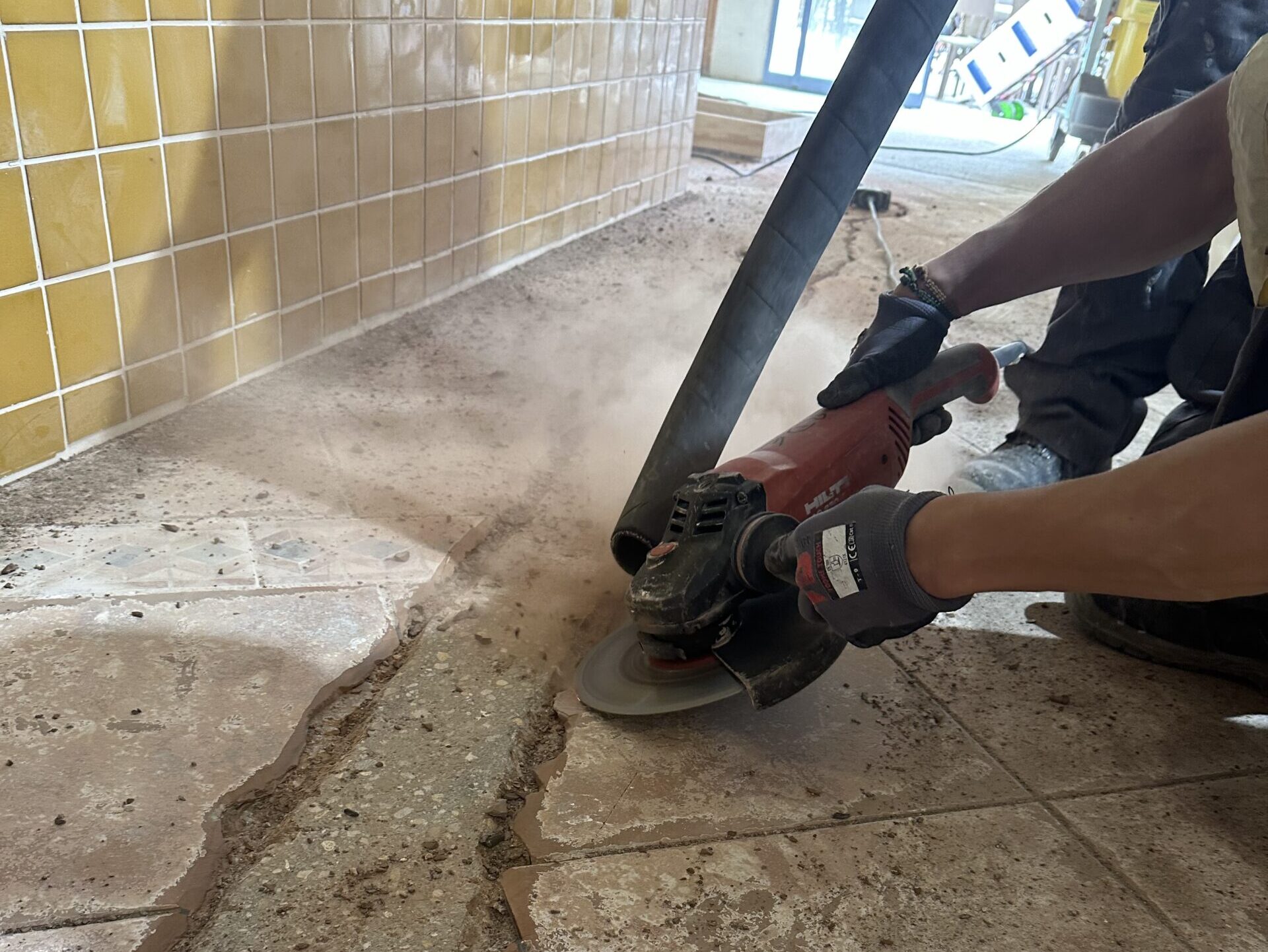 Operario usando radial para abrir juntas y fisuras en pavimento antes del tratamiento.