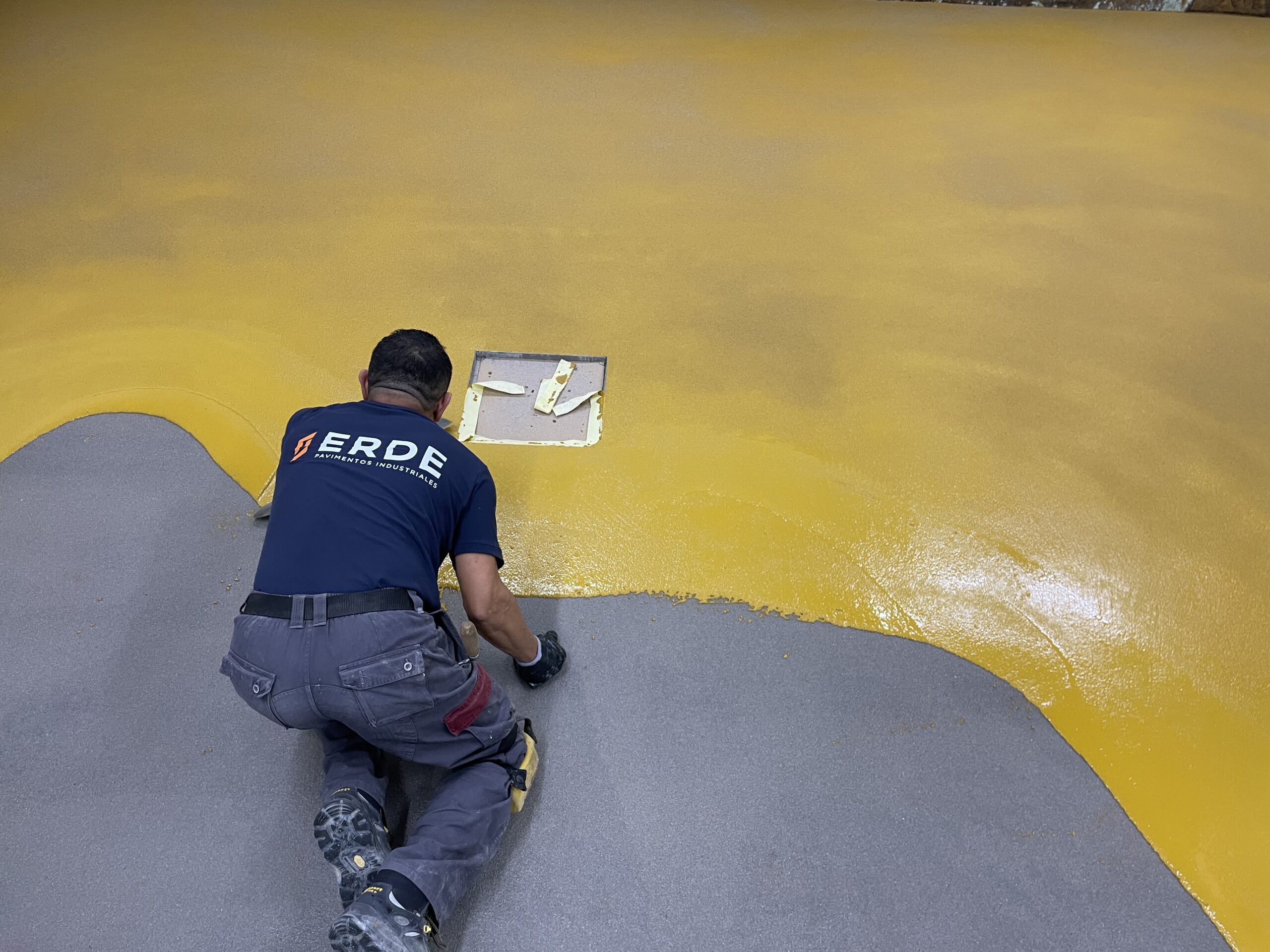 Trabajador aplicado capa de pavimento de color ocre con resinas de metacrilato
