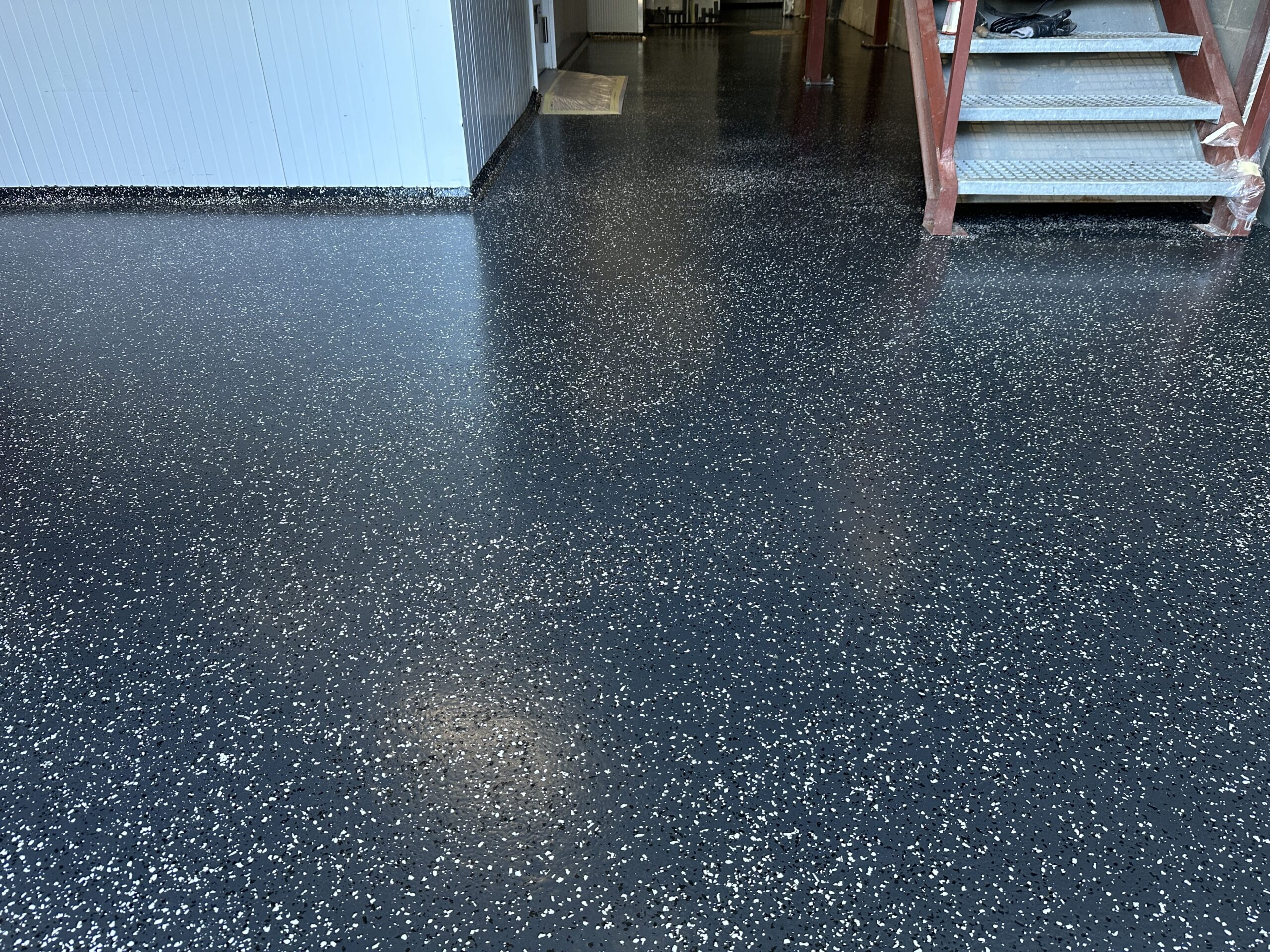 Pavimento negro con tratamiento antipolvo de resina de metacrilato con detalles blancos