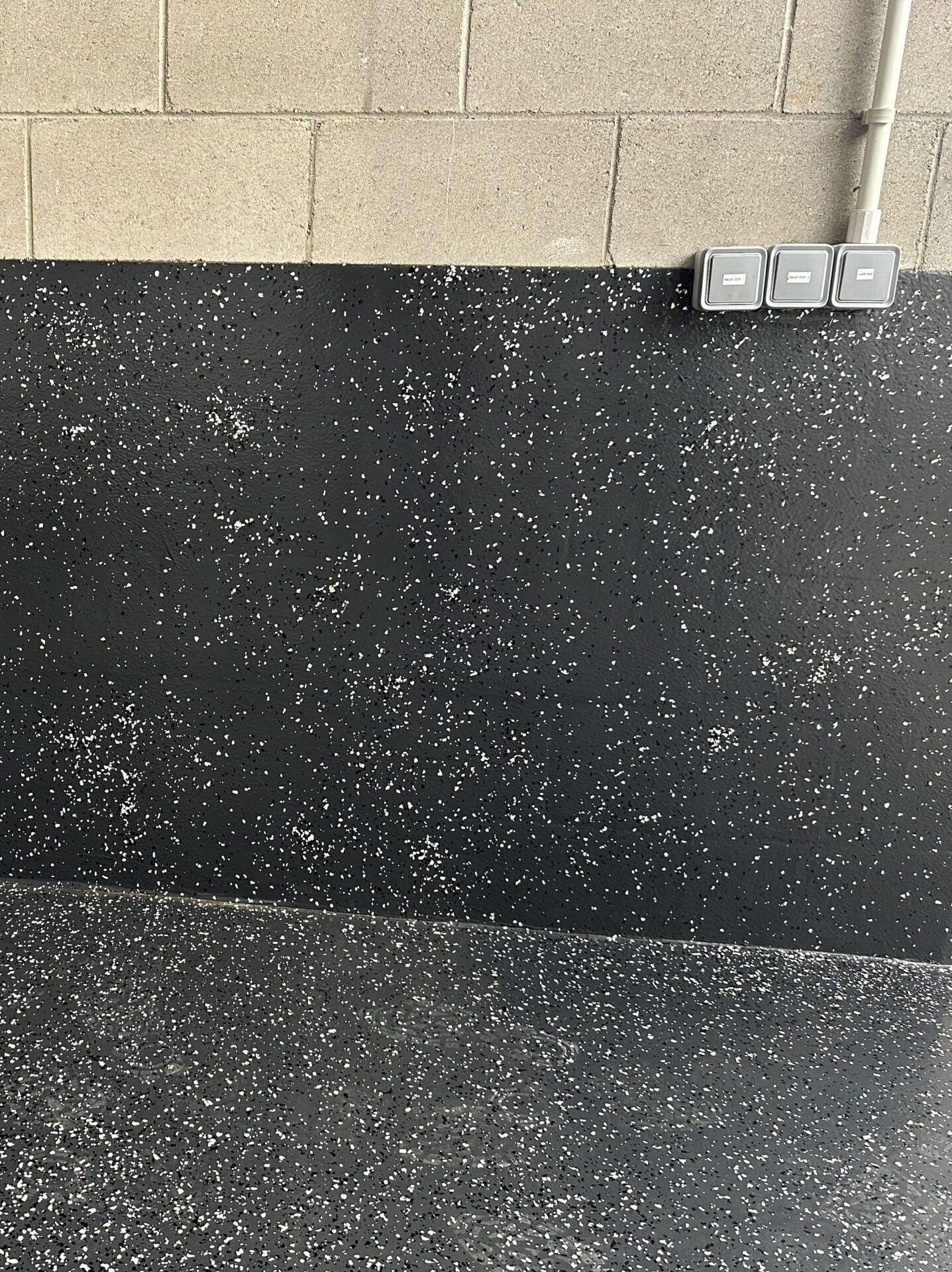 Pared reforzada pintada en negro con efecto moteado blanco.