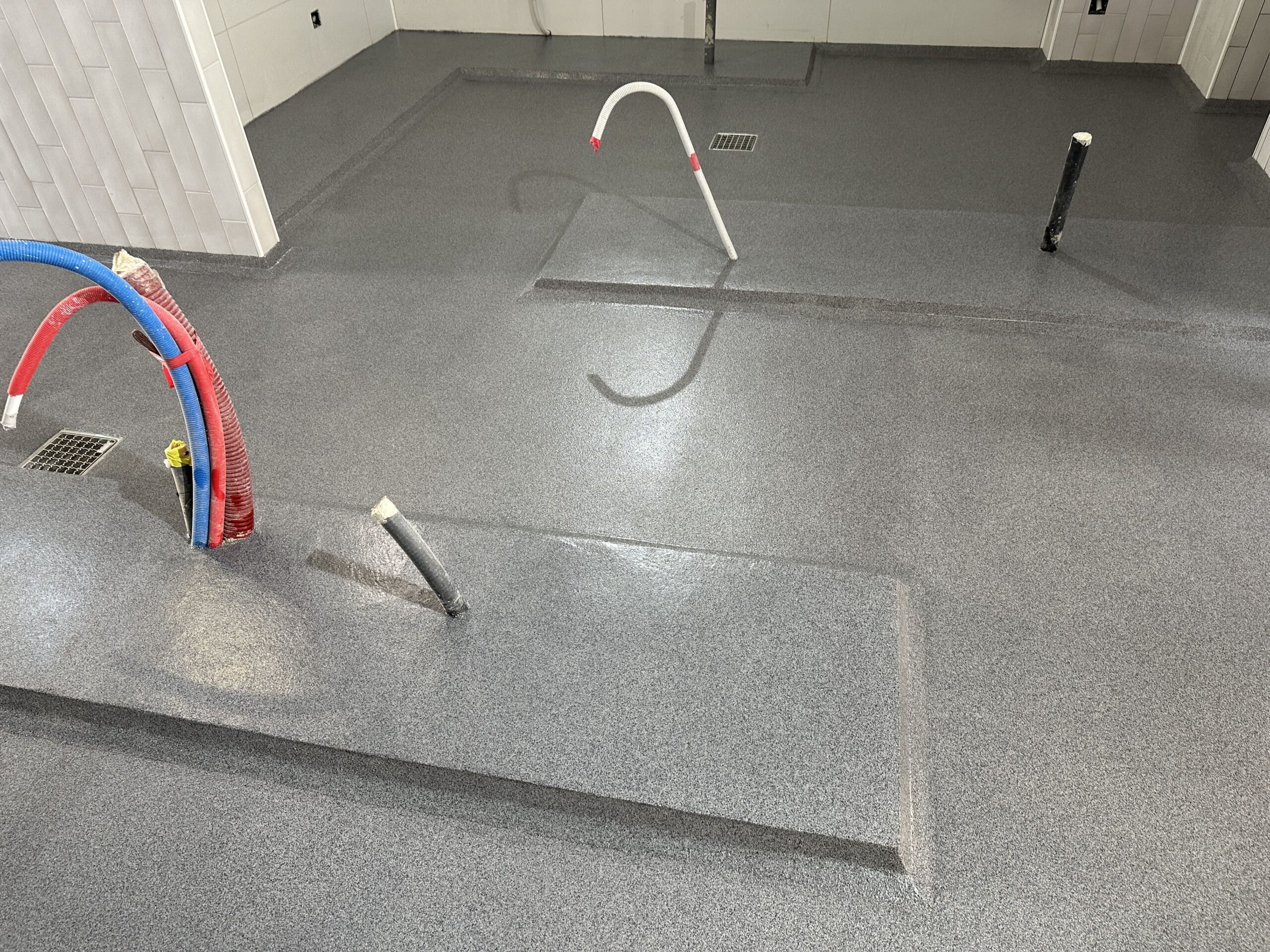 Pavimento continuo de resina de metacrilato en tono grisáceo y moteado negro.